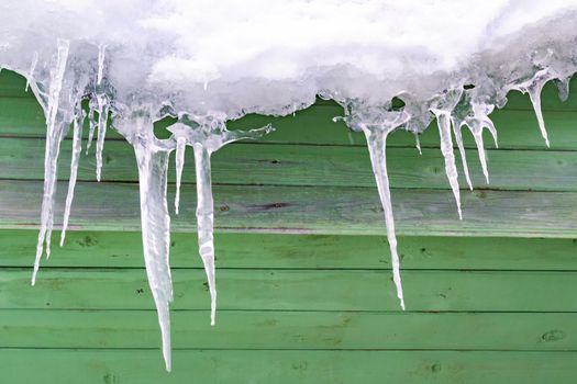 Icicles are icy against backdrop of old wooden wall.