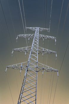The support of the high voltage line in winter. View from below. Gradient sky. Vertical image.