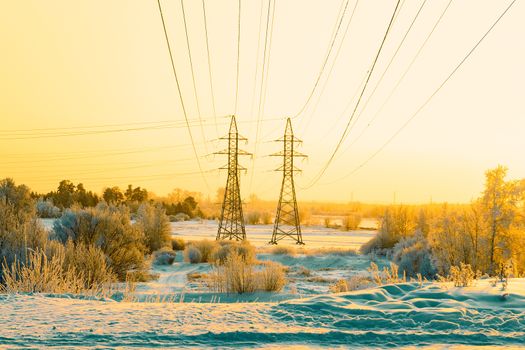 Two pillars of the high voltage line and wires through the riverplain in winter. Siberia.