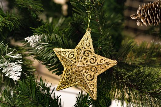 The star is a golden toy on the Christmas tree. A close-up view.