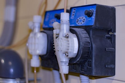 Industrial dispenser of chemical solution for water purification system at a car wash. View from the side.