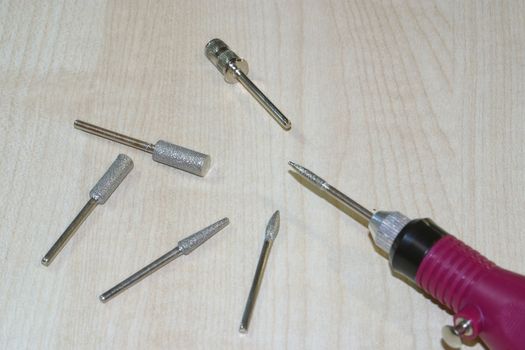 Set of milling cutters and milling machine on a wood background. Manicure and pedicure professional tools.