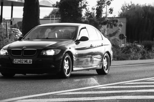 Black and white photo, concept of motion traveling car on asphalt road, front view of car on street. Bucharest, Romania, 2020