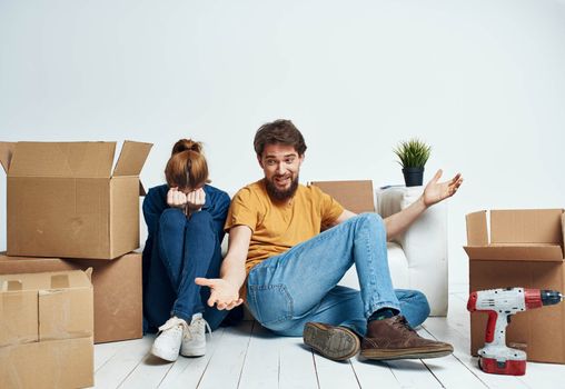 man and woman on the floors in a new apartment with boxes and tools for repair. High quality photo