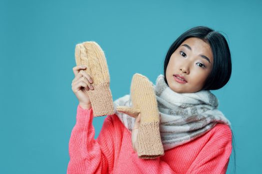 Asian woman with mittens in her hands on a blue background