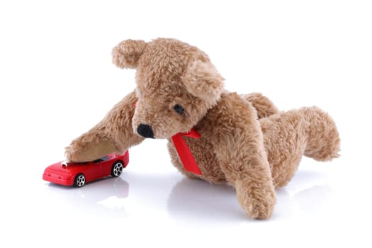 A Teddy bear playing with his toy car
