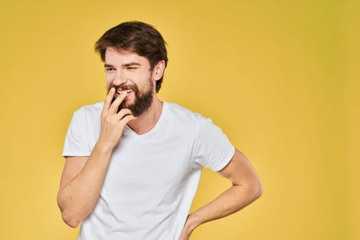 Bearded man white t-shirt emotions gestures with hands fun yellow background. High quality photo