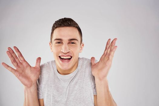 Man in a white t-shirt emotions gestures with hands close-up cropped view light background. High quality photo