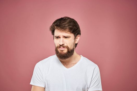 emotional man white t shirt sad facial expression pink background. High quality photo