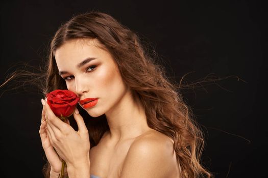 woman with a red rose on a dark background long hair makeup red lips. High quality photo