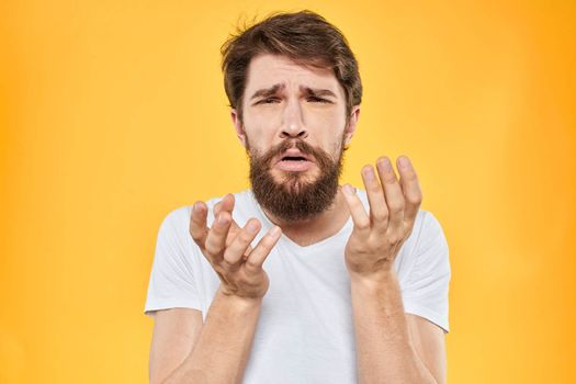 A man in a white t-shirt gestures with his hands studio lifestyle yellow background emotions. High quality photo