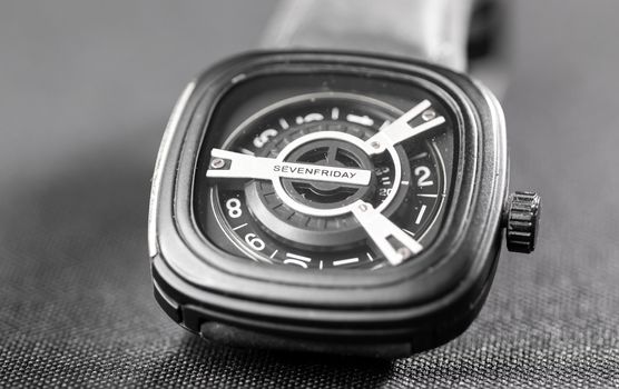 Square shaped used wrist watch on a slightly textured surface under studio lights macro photo