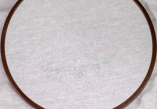 Wooden Embroidery hoop with a clean white piece of linen cloth and a simple design.