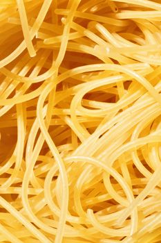 Dry pasta spaghetti detail ,a bunch of thin ribbons of pasta ,soft shadows ,bright colors