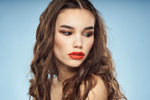 Elegant brunette fashionable hairstyle bright makeup naked shoulders close-up blue background. High quality photo