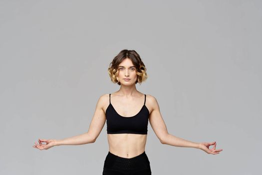 A slender woman is gesturing with her hands on a gray background Sport Fitness figure. High quality photo