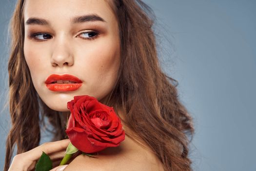 woman with a rose in her hands naked shoulders evening makeup red lips. High quality photo