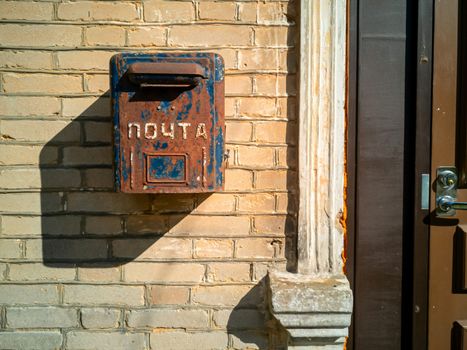 Old letterbox of Soviet era on the wall. Old post box. metal box for mail hanging on dirty wall.