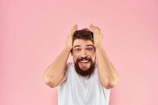 Man in white t-shirt gestures with hands emotions lifestyle cropped view pink background. High quality photo