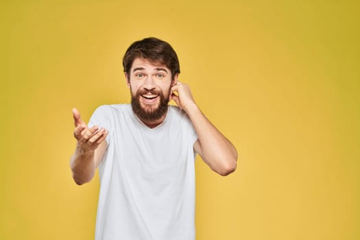 Bearded man in white t-shirt emotions close-up fun yellow background. High quality photo