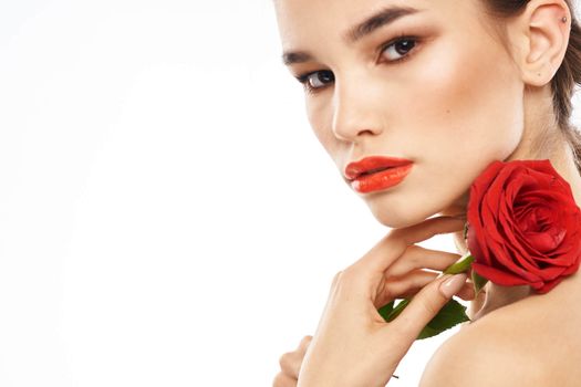 Beautiful woman with red rose near face makeup naked shoulders portrait. High quality photo