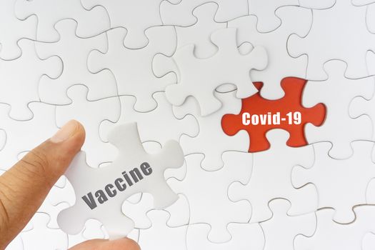 Hand holding jigsaw puzzle with text VACCINE and COVID-19. Covid-19 and Coronavirus concept