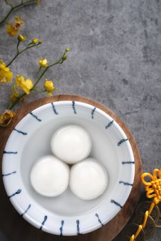 Top view of big tangyuan yuanxiao (yuan xiao tang yuan, glutinous rice dumpling balls) in a bowl on gray background for lunar new year festival food with copy space.