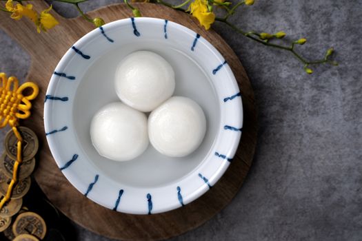 Top view of big tangyuan yuanxiao (yuan xiao tang yuan, glutinous rice dumpling balls) in a bowl on gray background for lunar new year festival food with copy space.