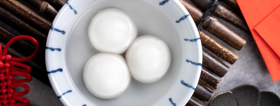 Top view of big tangyuan yuanxiao (yuan xiao tang yuan, glutinous rice dumpling balls) in a bowl on gray background for lunar new year festival food with copy space.