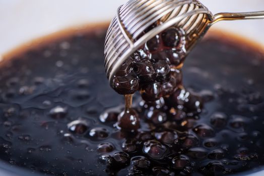 Cooking, boiling brown sugar flavored tapioca pearl balls, ingredient of bubble tea, preparing food and drink, close up, recipe cookbook steps design concept.