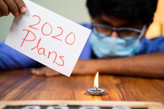 Sad frustated Man in medical mask burning 2020 plans - concept of failed 2020 plans due to covid-19 or coronavirus pandemic
