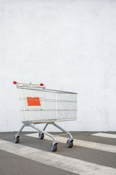 Empty Grocery Cart on the White Wall Store. Trolley at the Supermarket Background. E-commerce. Shopping Concept. Side View. Shopping Cart Trolley Stands near Mall with Copy Space. Black Friday Sale