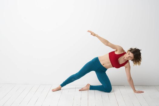 A woman in blue jeans practices yoga on a light background indoors and a slim figure in gymnastics. High quality photo