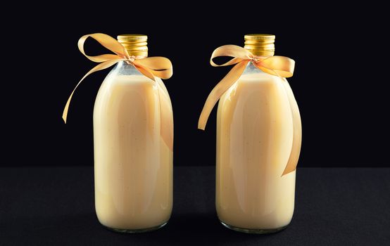 Two bottles of homemade eggnog on dark background