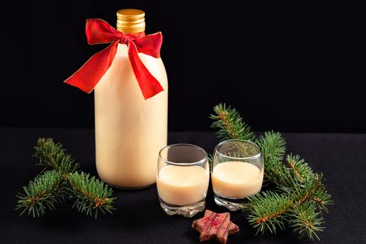 Homemade eggnog in bottle and two glasses with Christmas decoration on dark background