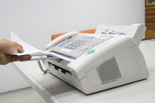 hand man are using a fax machine in the office, equipment for data transmission.