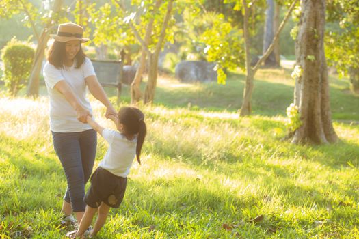 Young asian mother and little daughter playing the park with fun and happiness, family enjoy and relax and leisure together, mom and children smiling laughing in summer day.