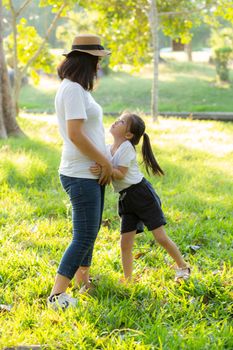 Young asian mother and little daughter playing the park with fun and happiness, family enjoy and relax and leisure together, mom and children smiling laughing in summer day.