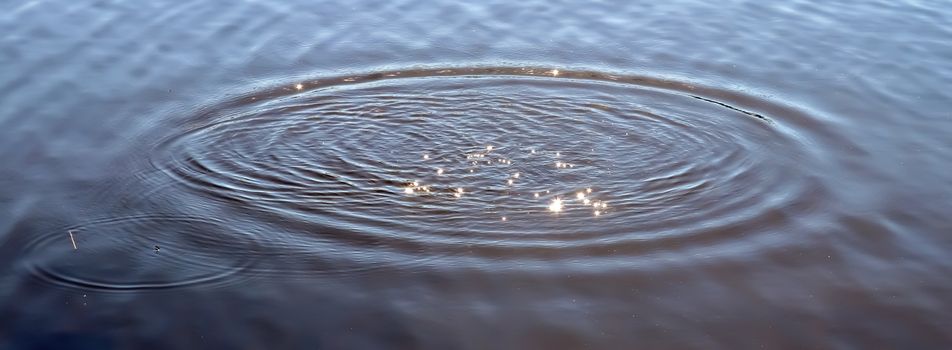 Beautiful water at a lake with splashing water and ripples on the surface with clouds and sky reflections