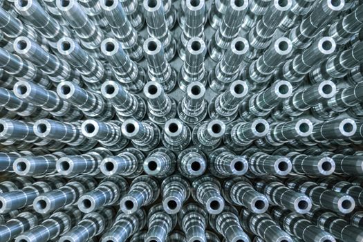 Shiny long steel parts full frame background, clean steel threaded rods after fine cnc turning. Standing vertically in a rows with selective focus in directly above perspective.