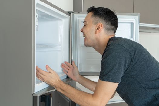 On a hot day, the guy cools with his head in the refrigerator. Broken air conditioner.
