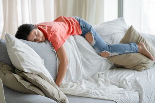 The girl fell asleep in an unusual position on the back of the sofa. Daytime sleep. Energy recovery.