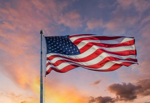 An american flag backlit by the sun against a blue sky with clouds