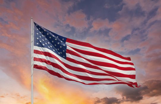 Large American flag blowing in the breeze against sky and clouds