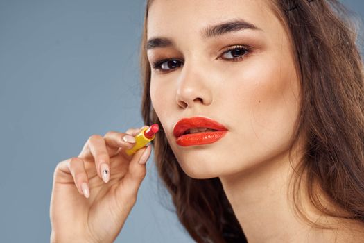 Woman with lipstick on a gray background brunette makeup with eye shadow on the eyelids. High quality photo