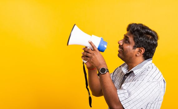 Asian happy portrait young black woman standing to make announcement message shouting screaming in megaphone, studio shot isolated on yellow background with copy space