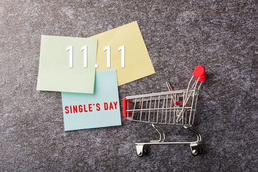 Above blank paper stick note list yellow and green with the shopping cart with 11.11 single's day text on paper on concrete table background, 11:11 Shopping reminder concept