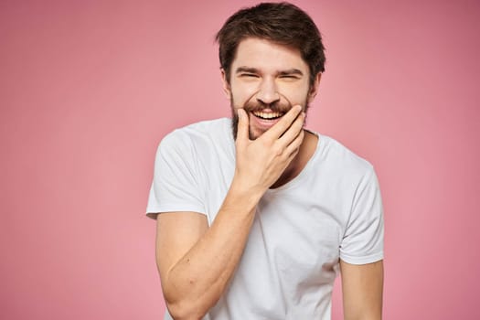 man in white t-shirt gesturing with his hands emotions fun pink background. High quality photo