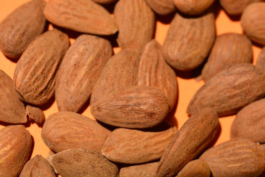 Raw almonds on orange paper background