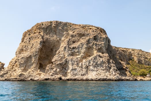 View from a motor boat on the mediterranean sea at the rocky coastline near Stegna on the eastside of Greek island Rhodes on a sunny day in spring